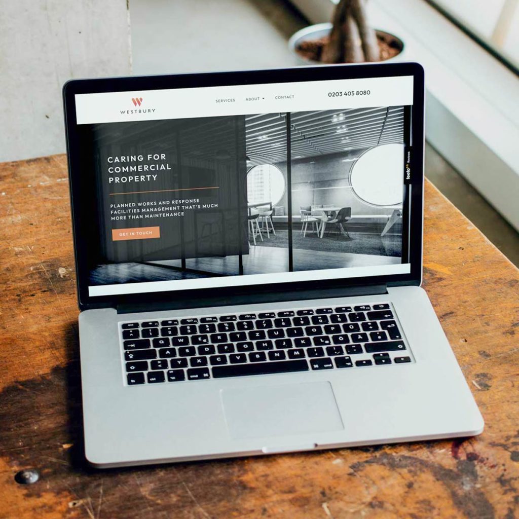 An open laptop displaying a website design sat on a workbench
